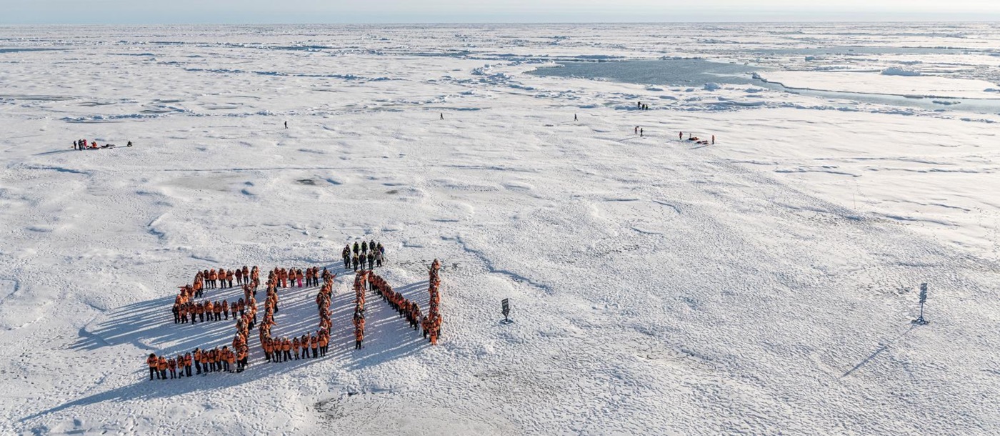 Passengers of a Ponant Arctic cruise making a 90 degree north formation in the North Pole