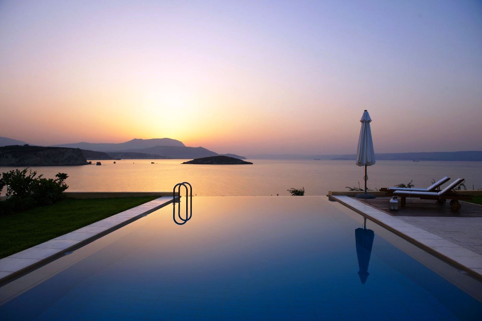 Swimming pool overlooking sea and mountains in the distance at sunset at villa anemos in crete