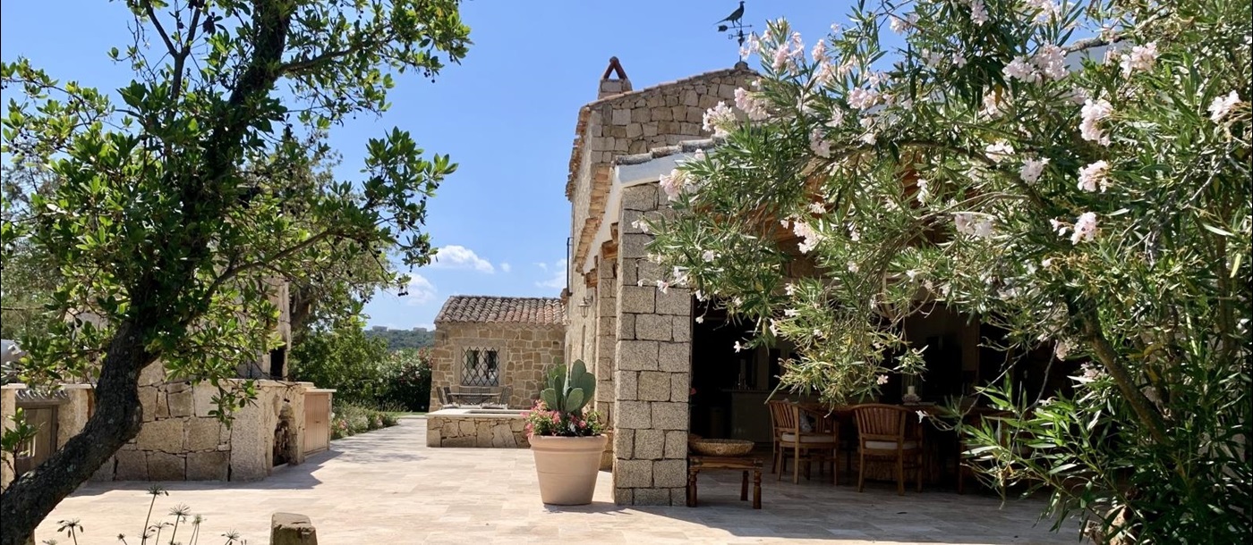 Garden with oleander, trees, cactus and outdoor dining areas at Villa Pantaleo on Sardinia, Italy