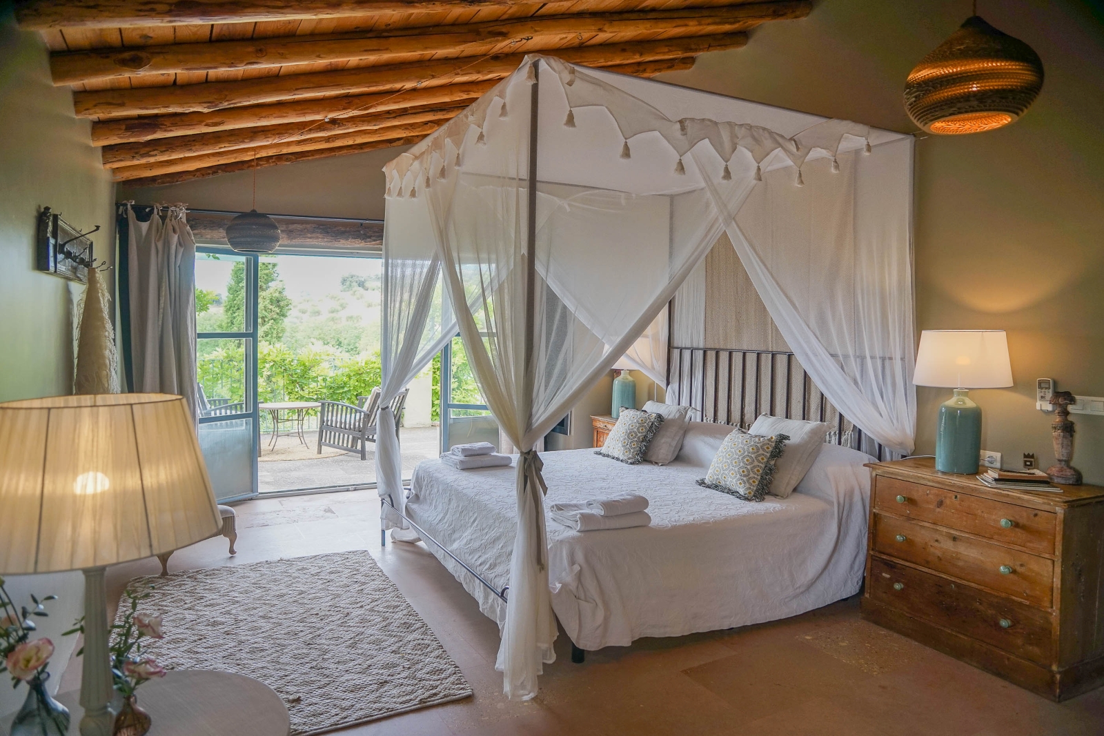 Master bedroom with four poster bed and extensive swing doors to a private terrace at luxury villa Pero di Ronda in Spain