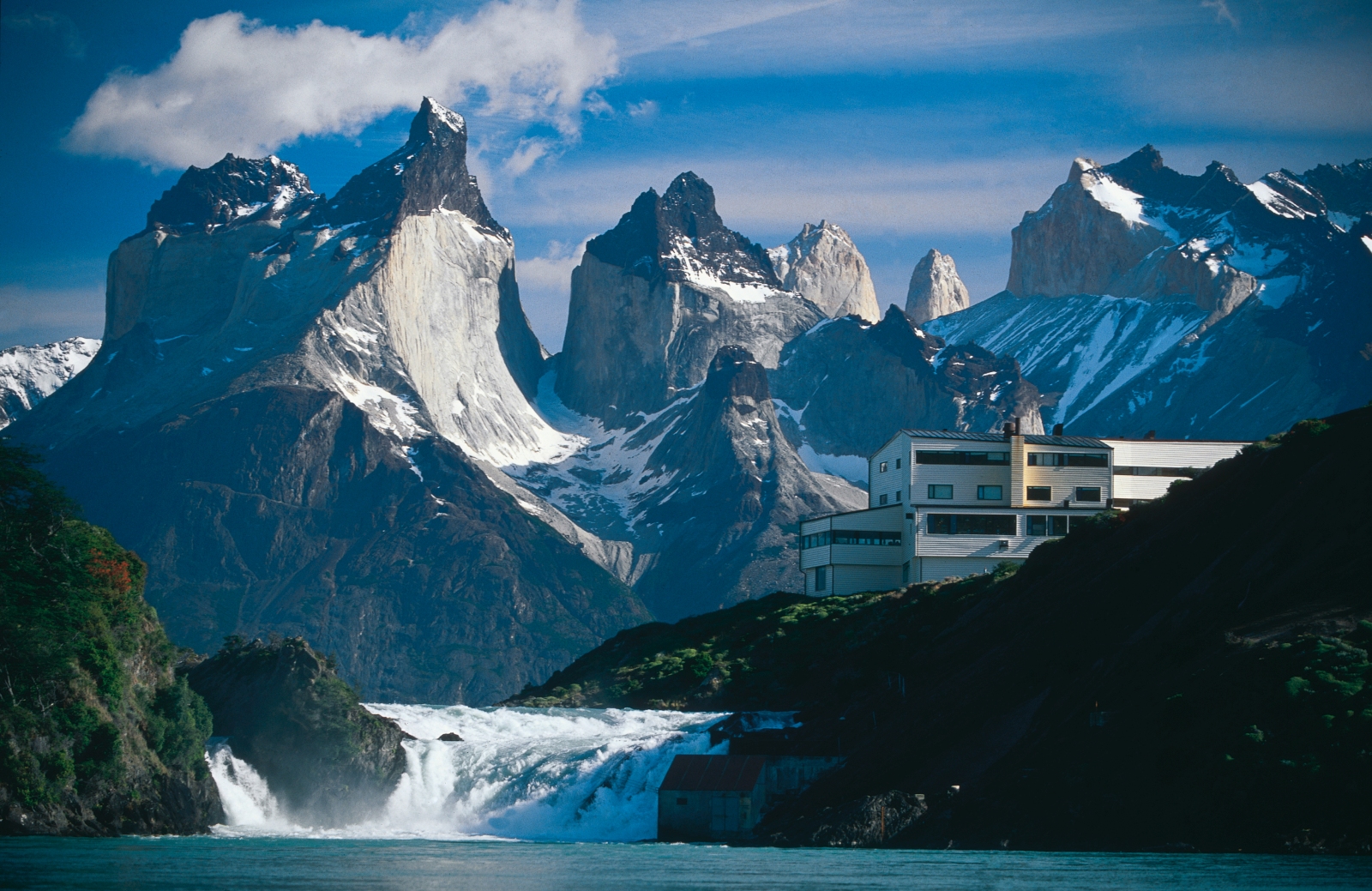 Exterior of Explora Patagonia with impressive mountain range and waterfall