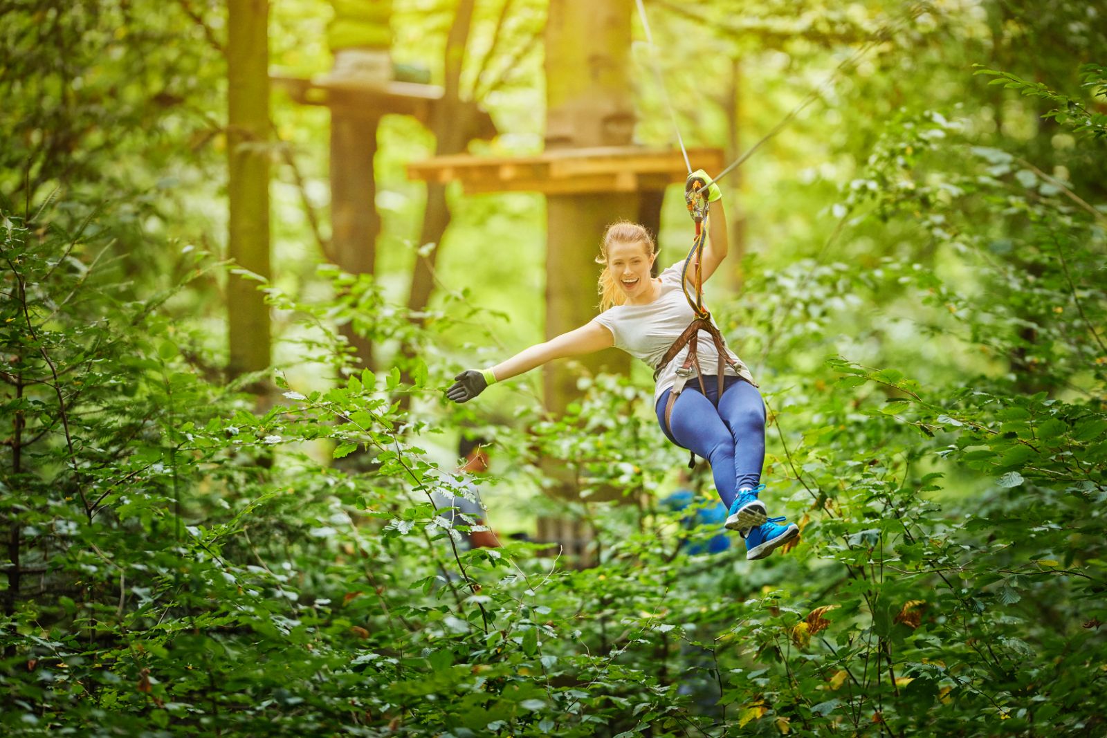 A lady canopy zip lining through a forest