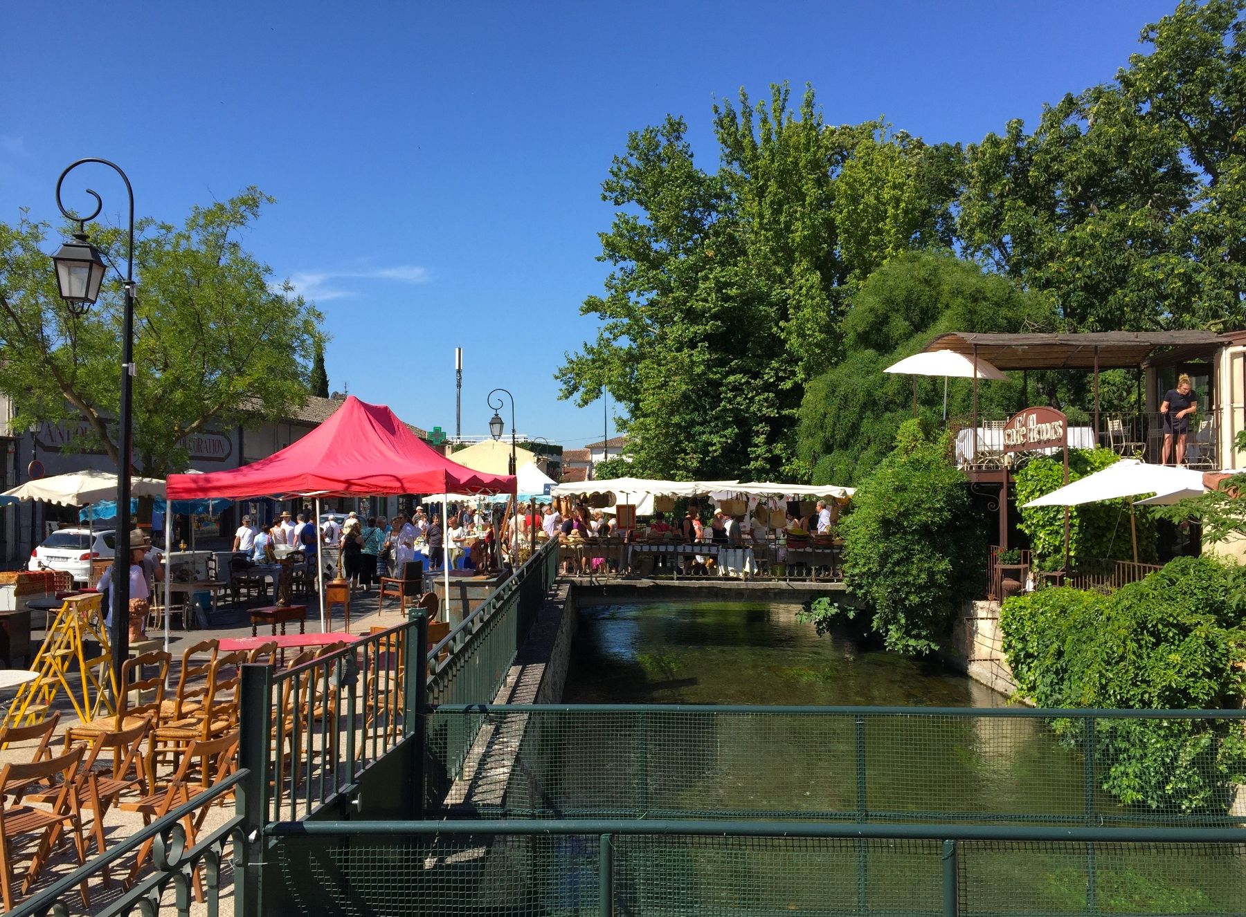 Market stalls and cafe by the river at L'Isle sur la Sorgue in Provence