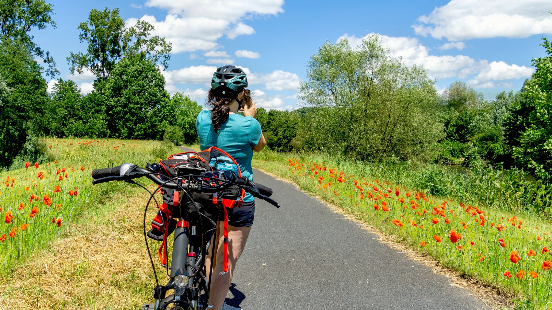 Lady on an e-bike on a rural road stopping to take a photo