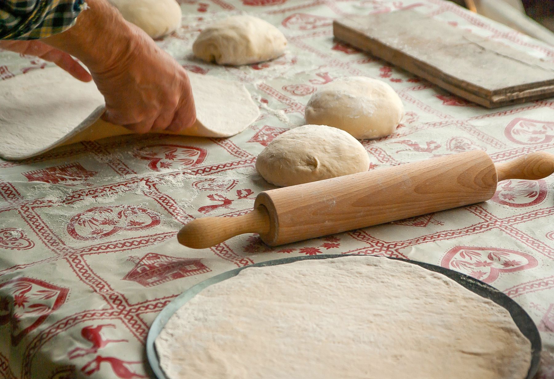 Lady preparing pizza dough with a rolling pin