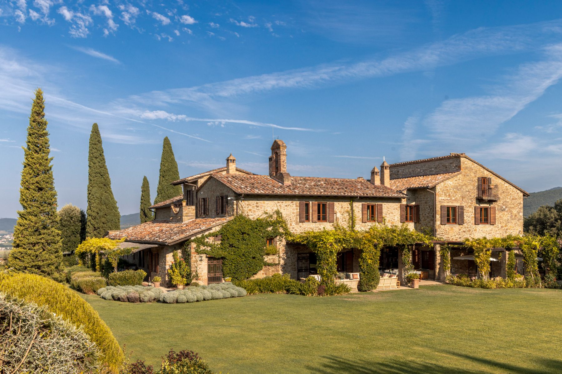 Front view of villa Il Convento in Umbria with view of trees and garden area