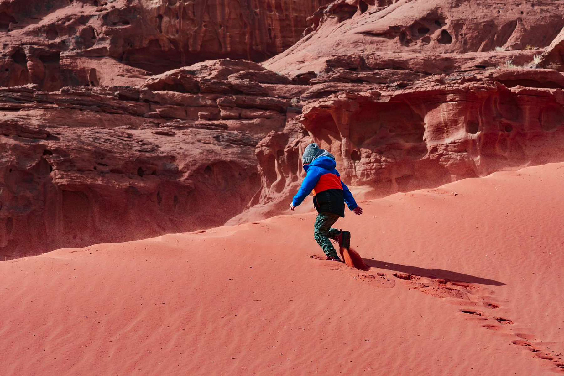 A child running on the red sands of the Wadi Rum in Jordan