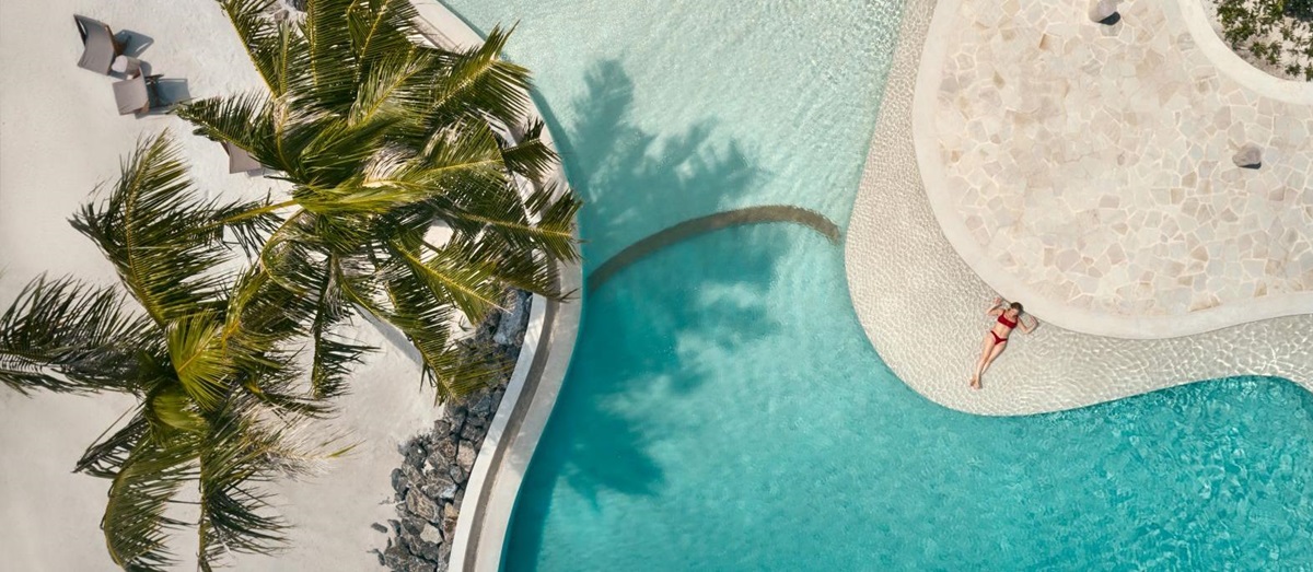 Aerial view of a guest floating in the pool at luxury resort Patina in the Maldives