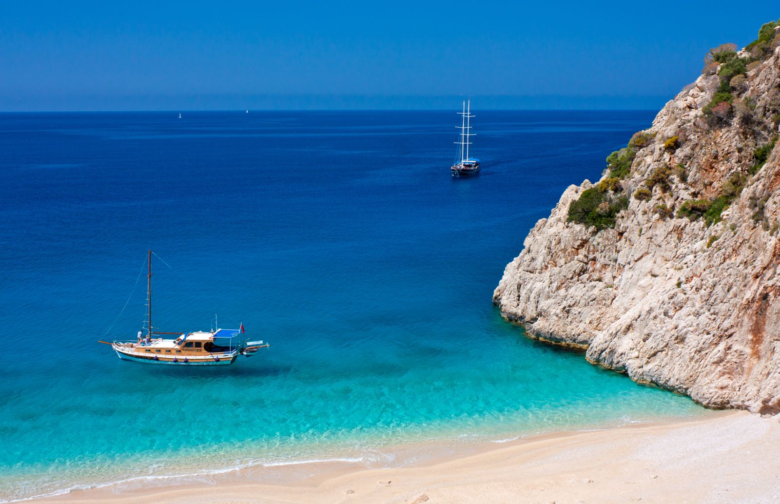 Gulets moored in turquoise waters off a pristine beach in Kalkan Turkey