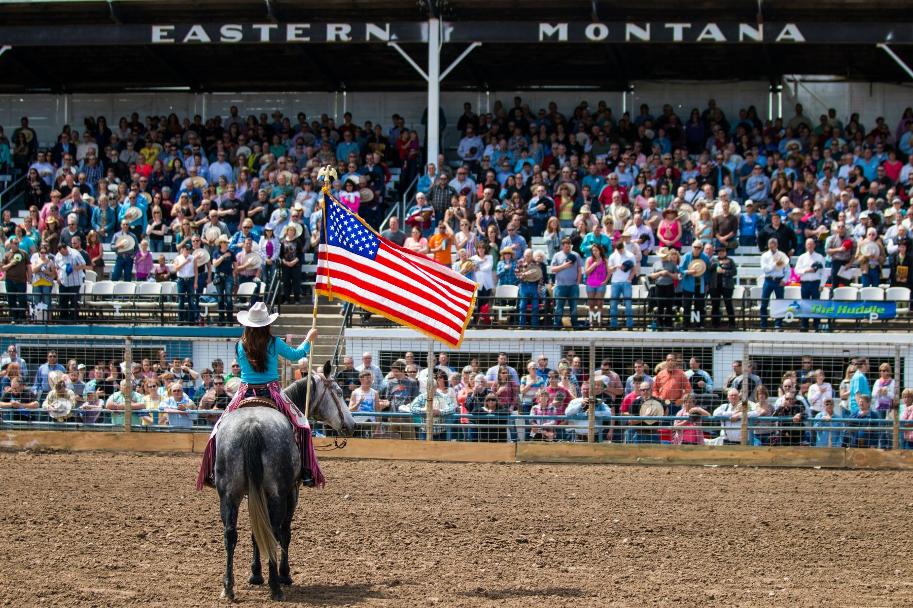 Rider holding a flag in front of spectators at a rodeo in the USA