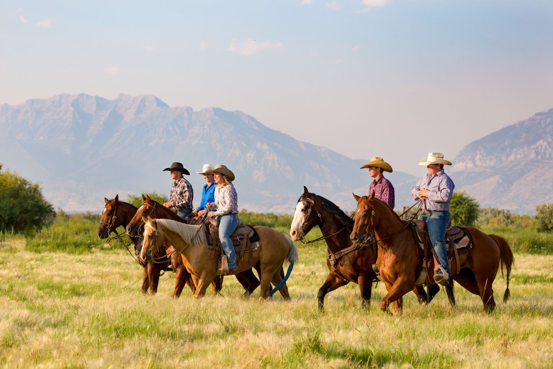 Group of people horse riding across a meadow in Utah