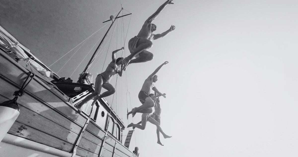 People jumping nto the sea from the side of a boat