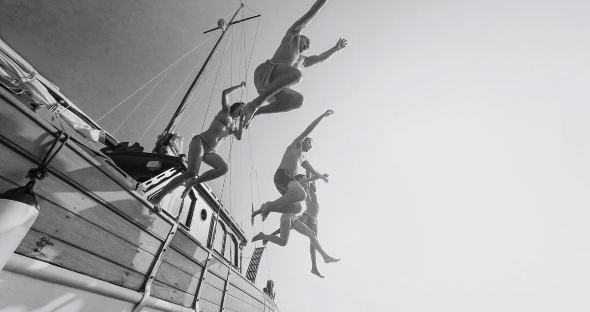 People jumping nto the sea from the side of a boat