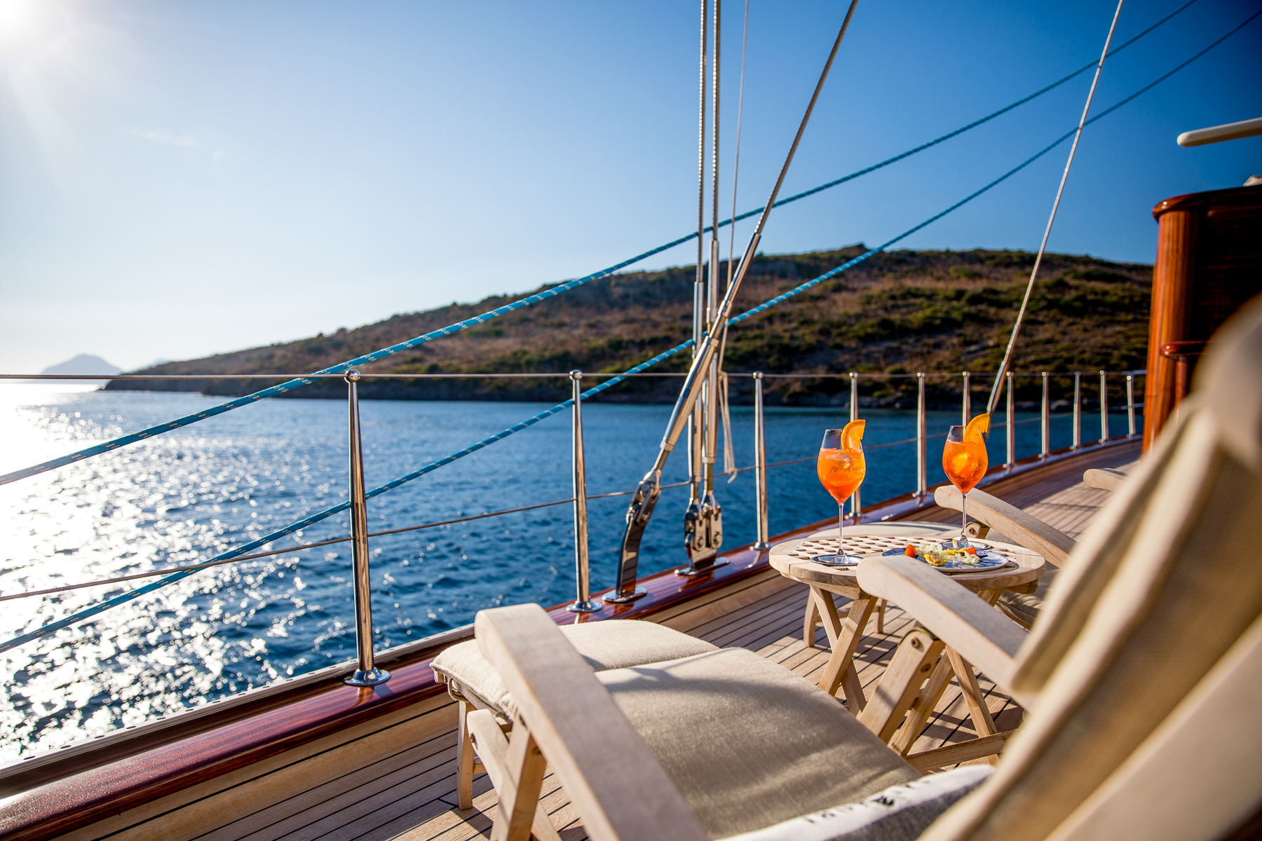 Drinks on a table next to loungers on the deck of the Satori luxury sailing yacht in Sicily